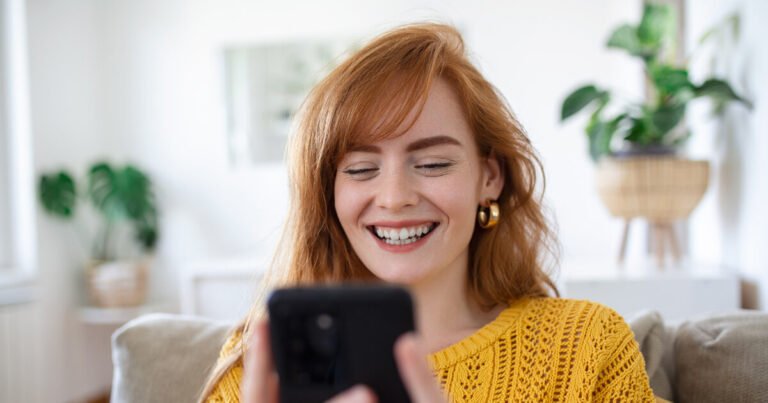 Ženska z nasmehom uporablja pametni telefon.